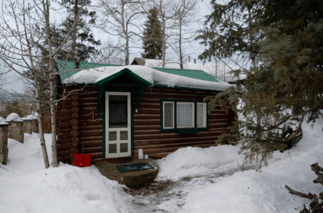 cabin with a green roof covered in snow