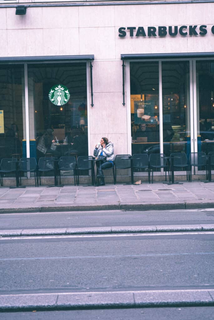 A lady sitting while talking to someone over the phone while at Starbucks