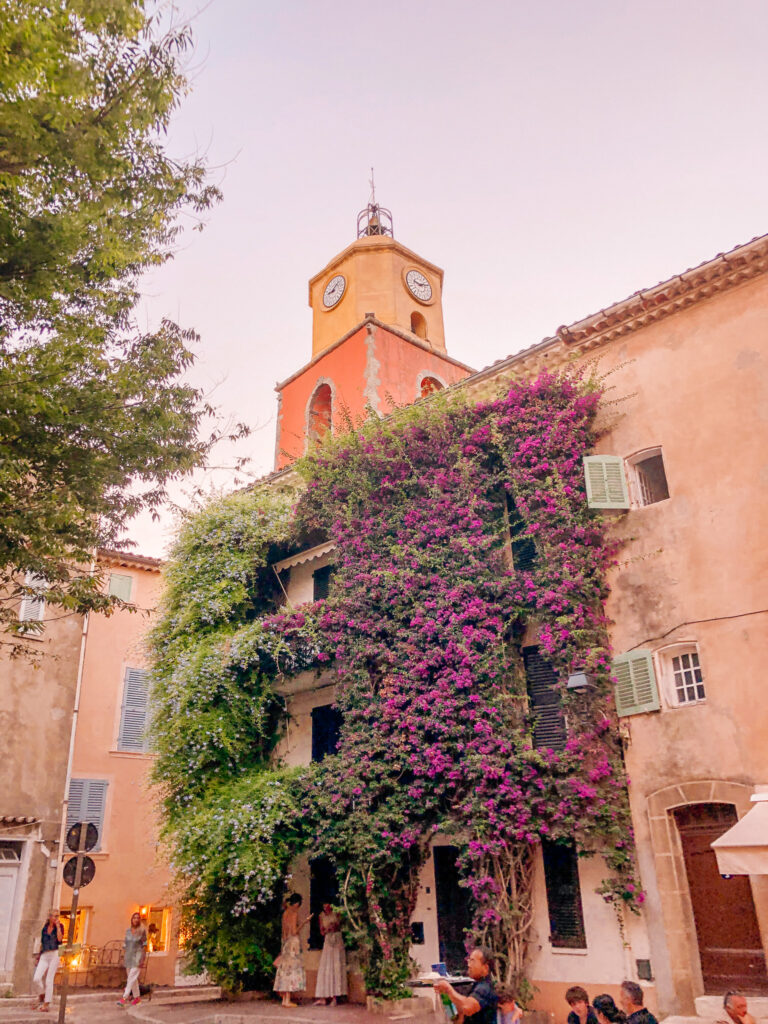 The Saint-Tropez bell tower above a house covered in purple bougainvillea